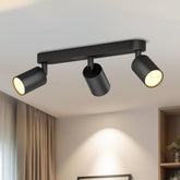 Black ceiling light fixture with three cylindrical lights on a ceiling.